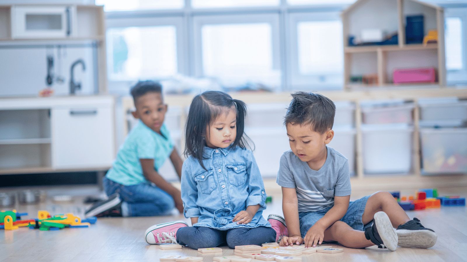 three children sitting on the floor of a daycare center